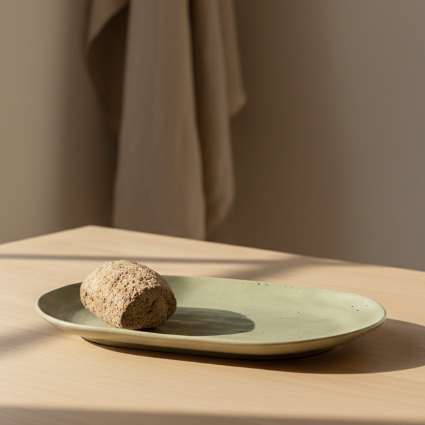 Green ceramic plate with a piece of bread on a wooden brown surface and on a beige background. 