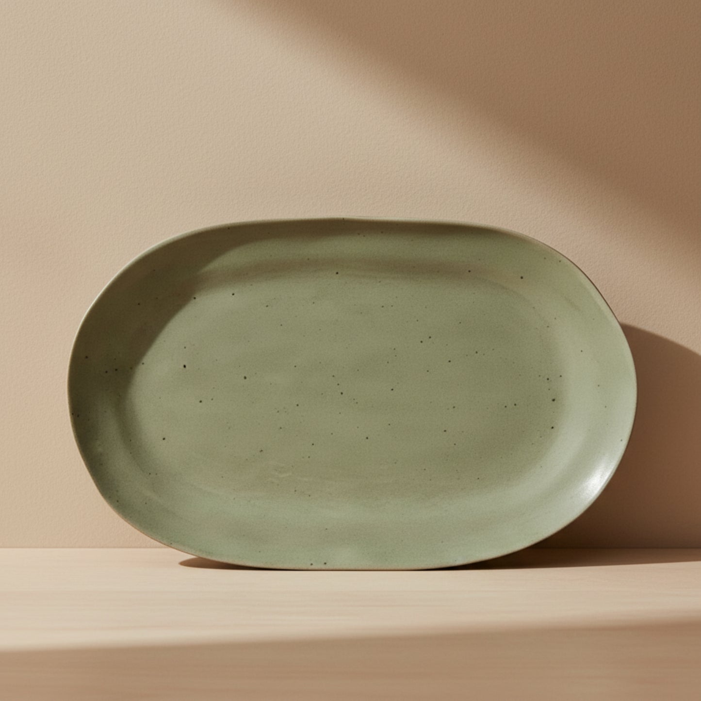 Green ceramic plate on a wooden kitchen surface and on a beige background. 