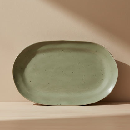 Green ceramic plate on a wooden kitchen surface and on a beige background. 