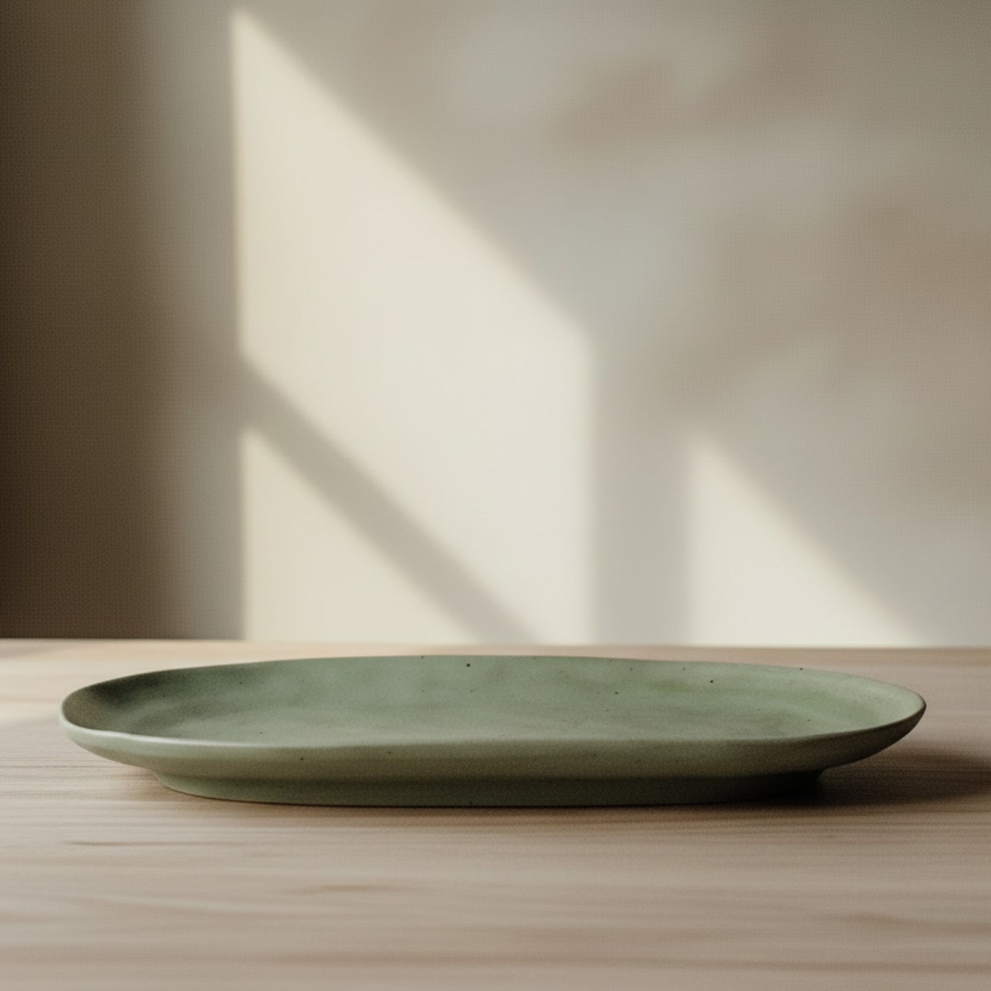 Green high-quality ceramic plate on a wooden surface and on a white-bage wall background. 