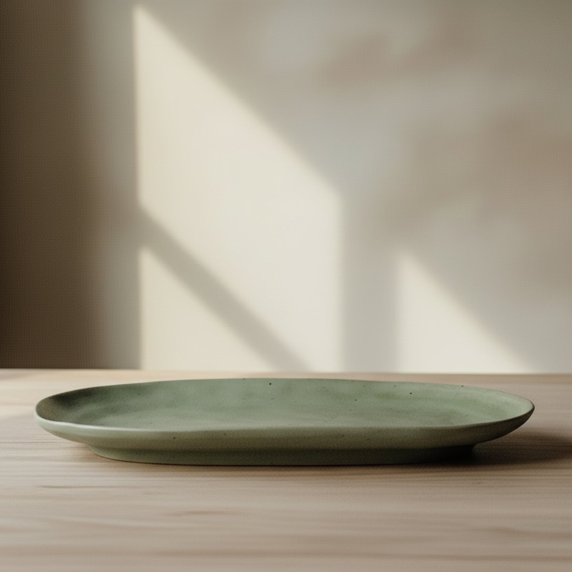 Green high-quality ceramic plate on a wooden surface and on a white-bage wall background. 