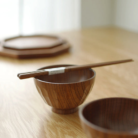 Wooden bowl with chopsticks on a wooden table. Natural and warm decor styling. 