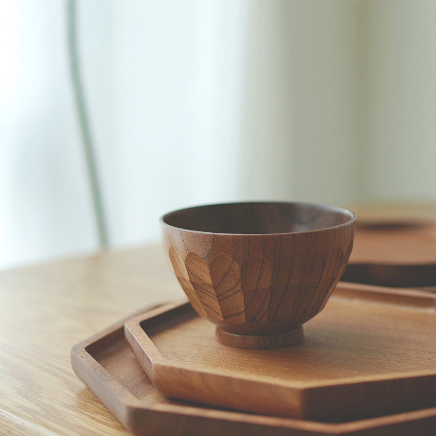 Handmade hammered wooden bowl on a wooden tray with a warm blurred background. Earthy and warm ambience. 