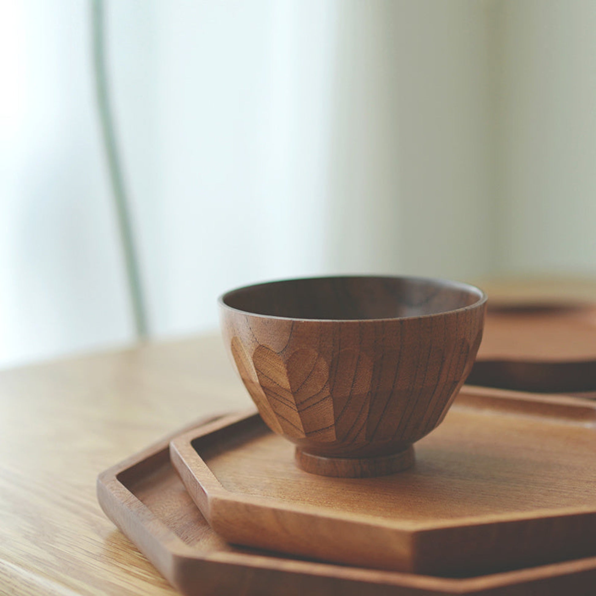 Handmade hammered wooden bowl on a wooden tray with a warm blurred background. Earthy and warm ambience. 