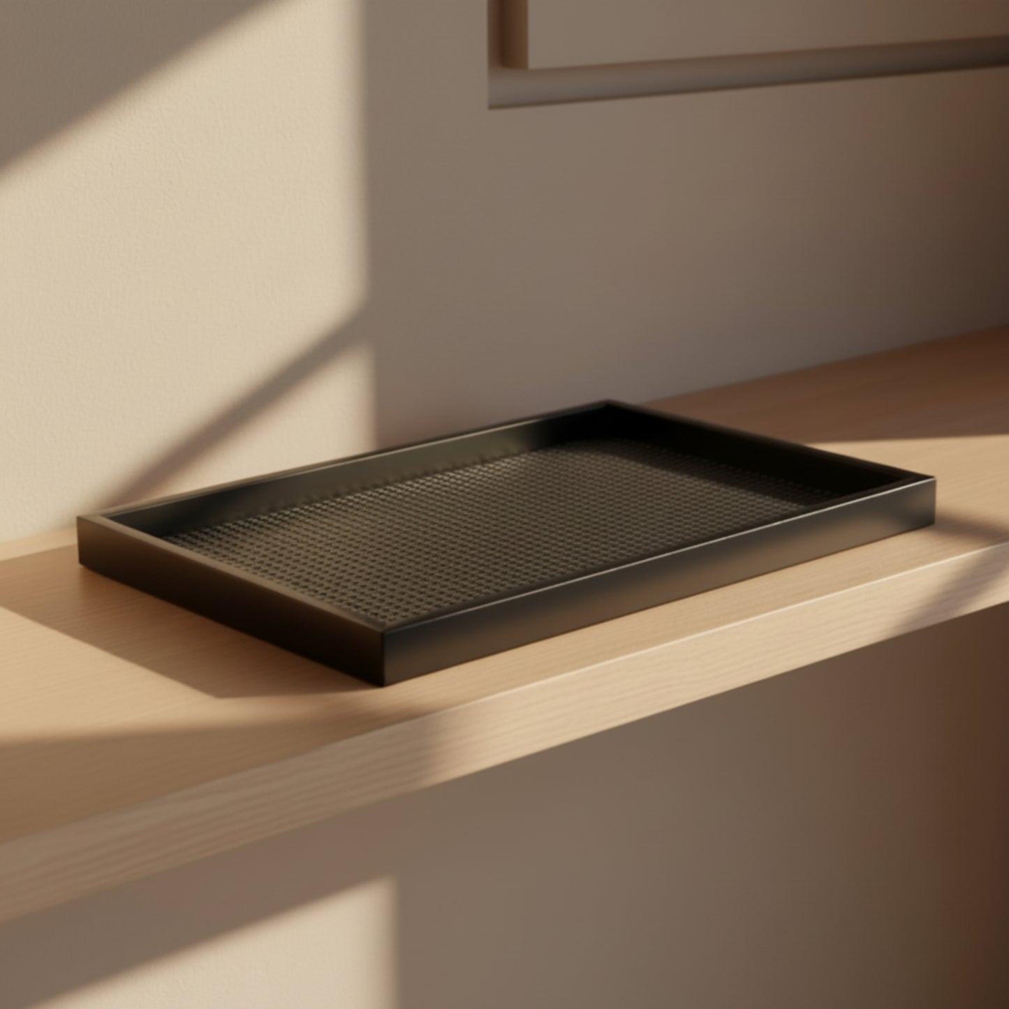 Handmade black rectangular wooden rattan tray on a wooden surface with soft shadows and a beige wall in the background. Warm and earthy home ambience. 