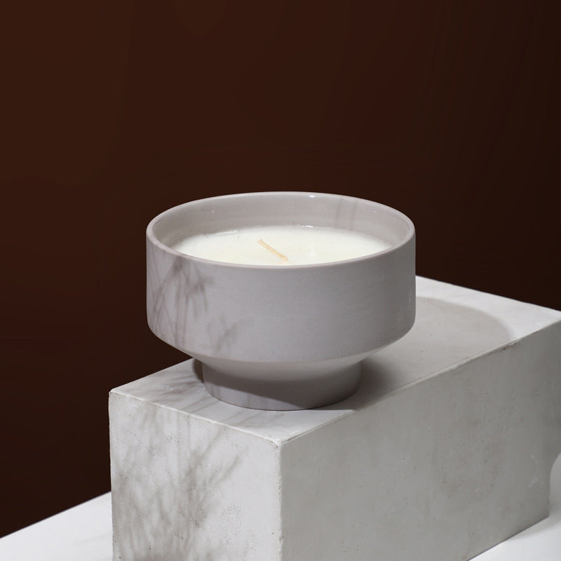 marble light grey candle bowl on a marble light grey surface on a brown background. Scandinavian decor simplicity. Minimalist handmade scented candle. Marble candle is in the center. 