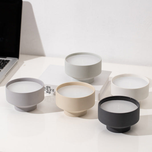 Set of five ceramic bowls in different colors on a white surface and a white wall background. With a laptop in the picture. Scandinavian decor simplicity. Minimalist handmade scented candles. 