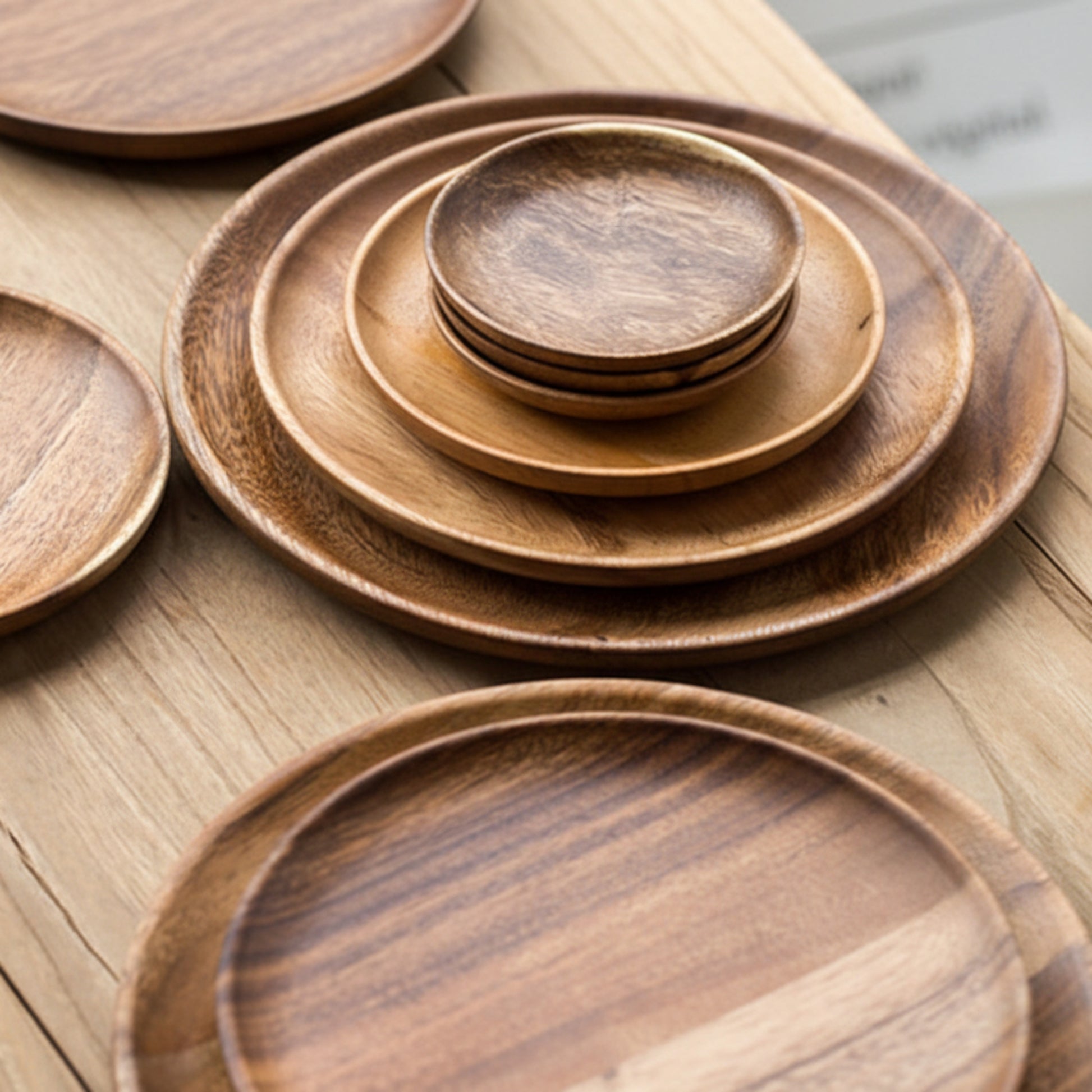 Set of wooden plates of different sizes on a wooden surface. Walnut tableware with natural grain and minimalist design. 