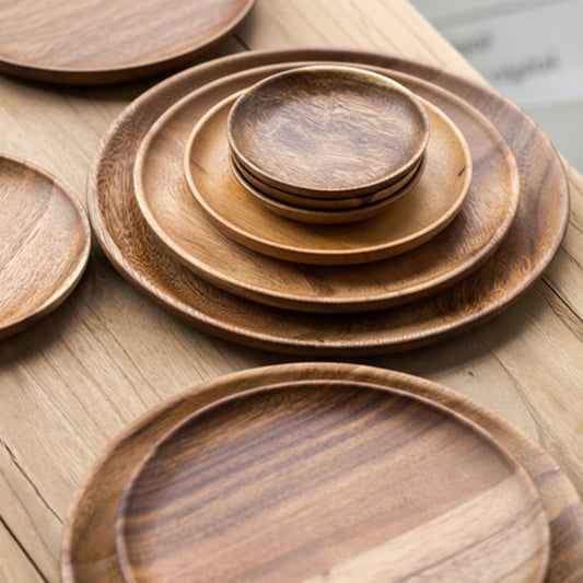 Set of wooden plates of different sizes on a wooden surface. Walnut tableware with natural grain and minimalist design. 