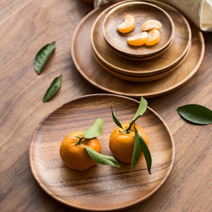 Wooden plates with mandarins on a wooden surface. Walnut tableware with natural grain and minimalist design. 