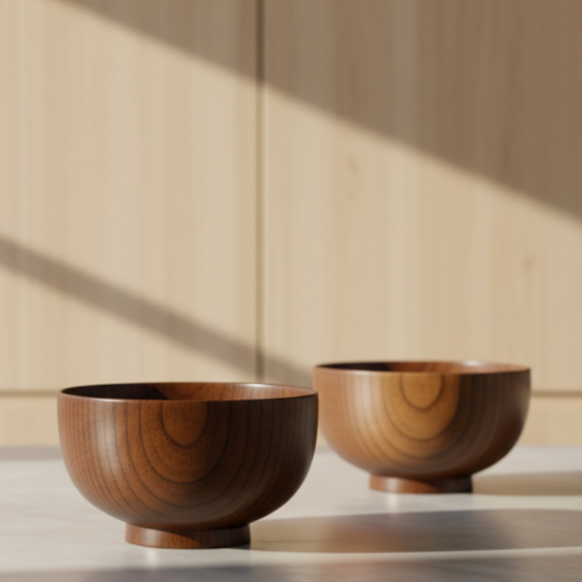 Two wooden bowls on a reflective kitchen surface with a neutral and wooden background. Solid wood. Japanese style. Earthy and natural. 