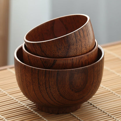 Set of three wooden bowls stacked on a bamboo mat. Solid wood. Japanese style. Earthy and natural. 