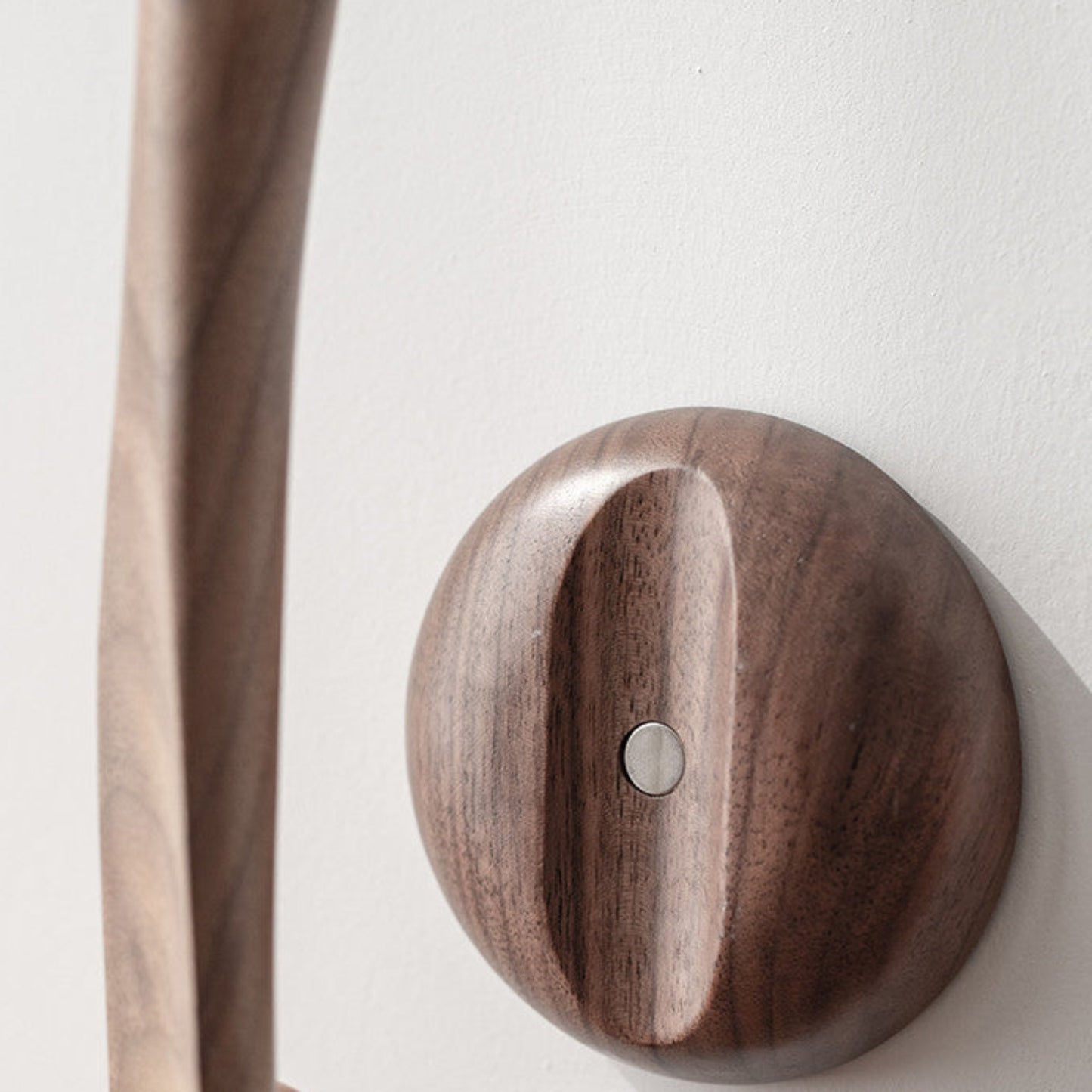 Wooden black walnut solid wood magnetic shoehorn close up on a white wall background. Brown, earthy and natural decor. 