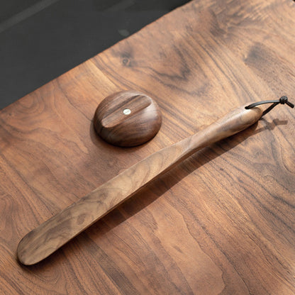 Wooden black walnut solid wood magnetic shoehorn on a wooden surface. Brown, earthy and natural decor. 