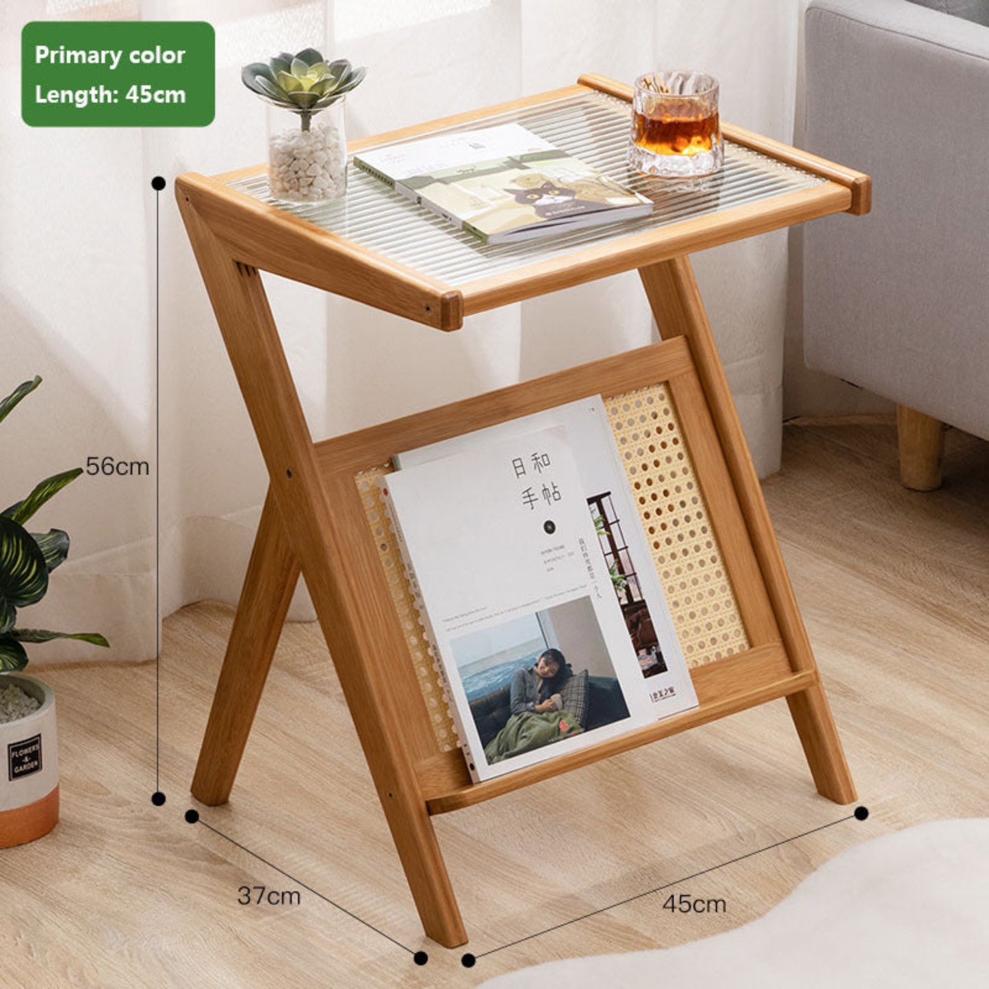 Wooden side table with glass top, books, and a glass of tea in a room setting on a wooden floor. Minimalist Japanese bamboo furniture on a wooden floor and a white curtain in the background. Clean lines, natural materials, and timeless pieces that bring warmth and balance to every home. With measurements. 
