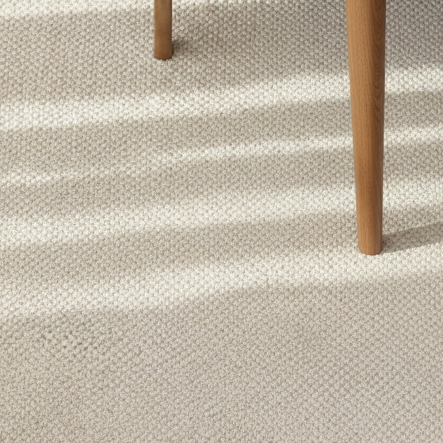 Beige wool woven carpet with a wooden stool on top. Warm, earthy and beige ambience. 