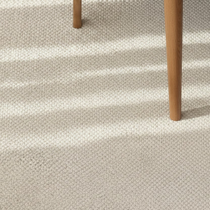 Beige wool woven carpet with a wooden stool on top. Warm, earthy and beige ambience. 