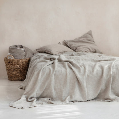 Bed with light gray plain linen bed sheet and pillows in a minimalistic earthy room.
Earthy and natural home and bed decoration. 
