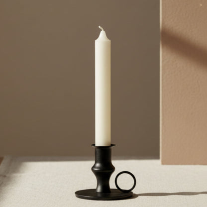 Black candle holder with a white candle on a neutral background. Minimalistic home decor. 