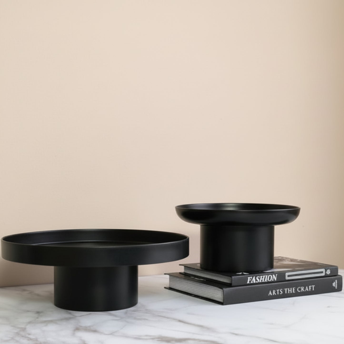 Two black ceramic bowls on a grey marble surface and beige background. Minimalist home decor. Timeless and minimalist design. Two books on the grey marble surface. 