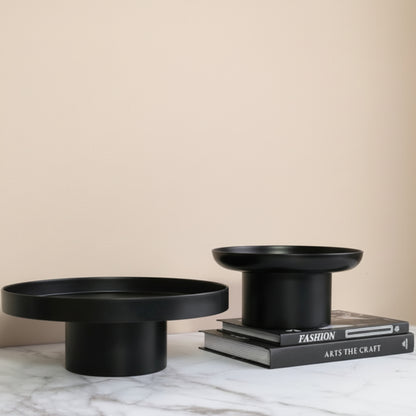 Two black ceramic bowls on a grey marble surface and beige background. Minimalist home decor. Timeless and minimalist design. Two books on the grey marble surface. 
