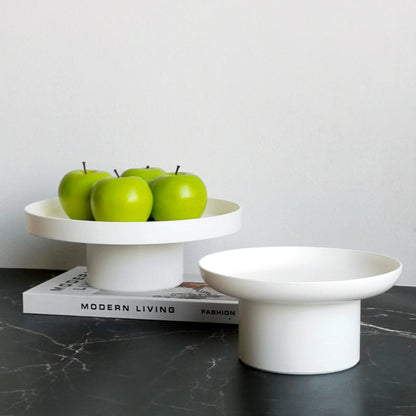 Two white ceramic cake stands with four green apples on a dark grey marble surface. Minimalist home decor. Timeless and minimalist design. 