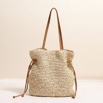 Woven beige straw bag with brown straps on a light beige background and a white surface. Natural chic look. Natural decor styling. Natural accessories. 