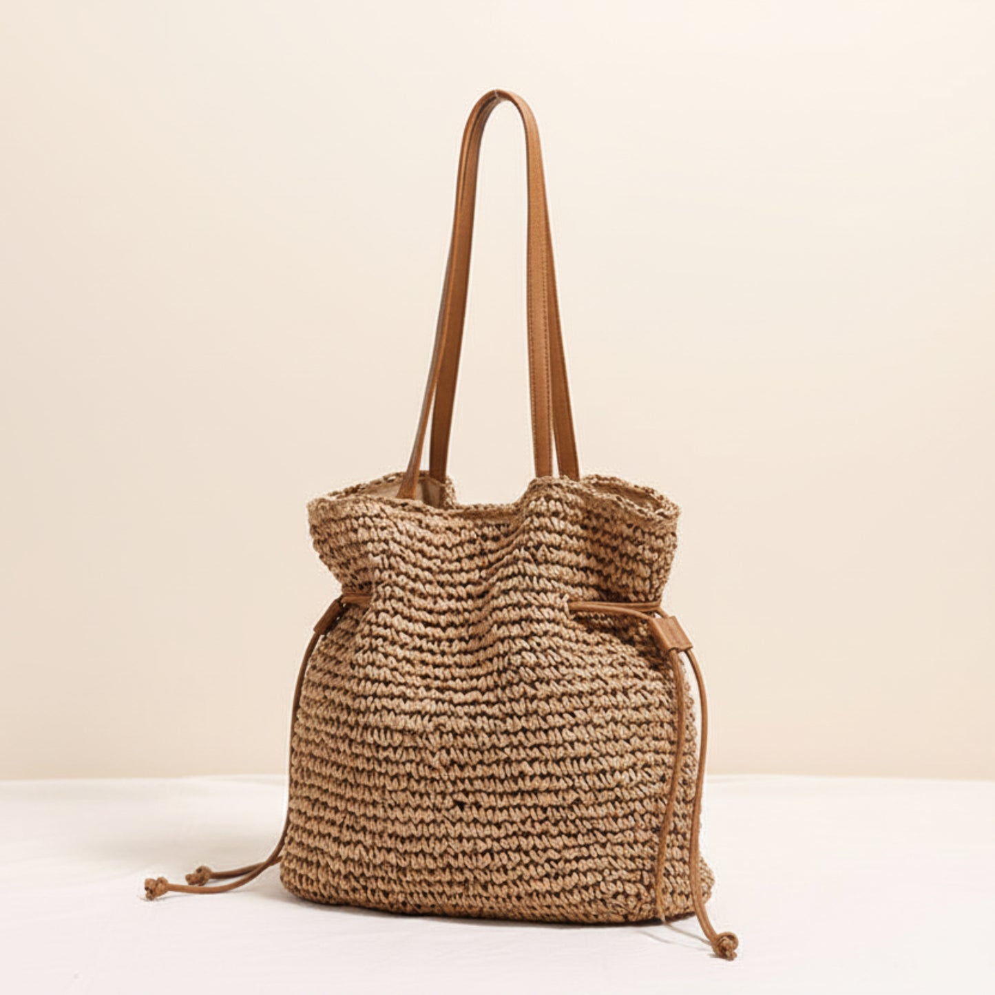 Woven coffee brown color straw bag with brown straps on a light beige background and a white surface. Natural chic look. Natural decor styling. Natural accessories. 