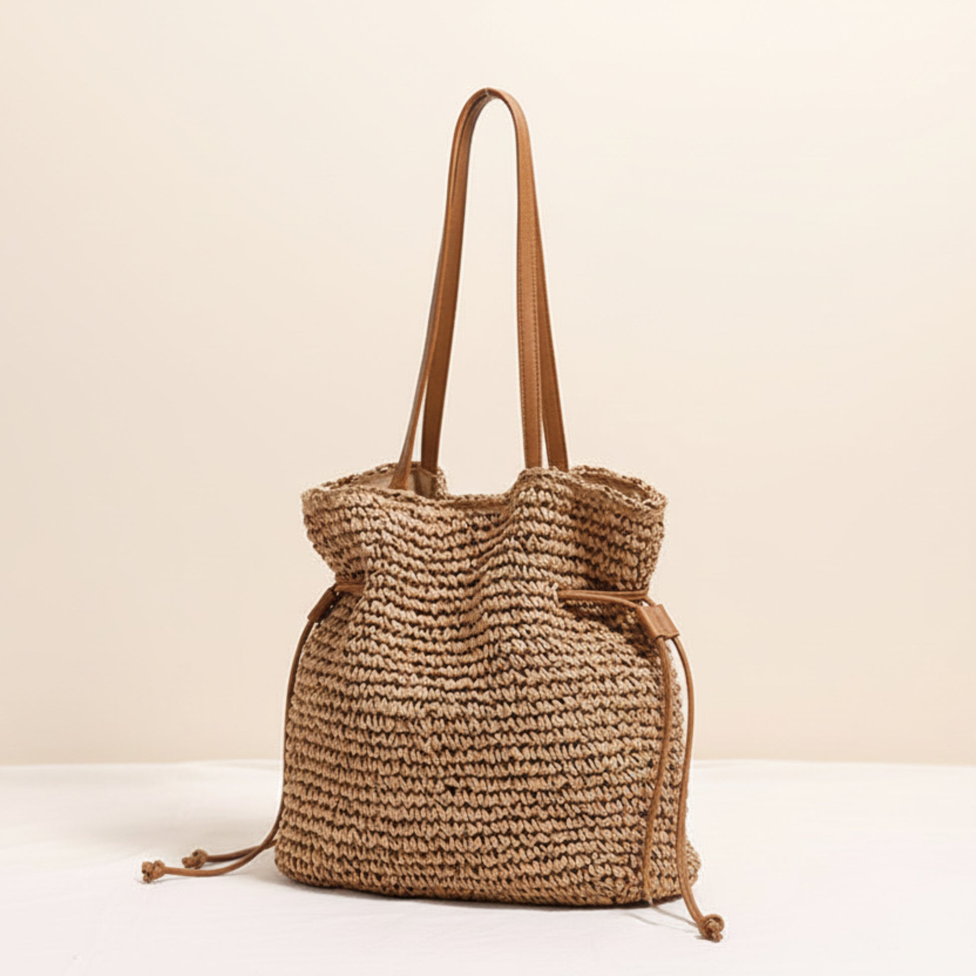Woven coffee brown color straw bag with brown straps on a light beige background and a white surface. Natural chic look. Natural decor styling. Natural accessories. 