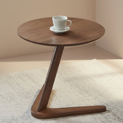 Wooden side table with a white cup and saucer on a beige-grey carpet against a beige wall. 