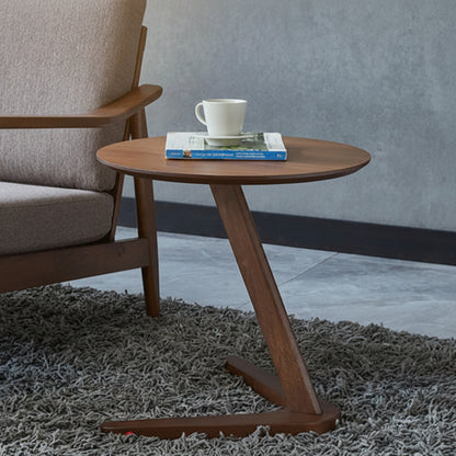 Wooden side table with a cup and book next to a gray armchair on a textured rug. Grey wall background. Minimalist nordic design. 