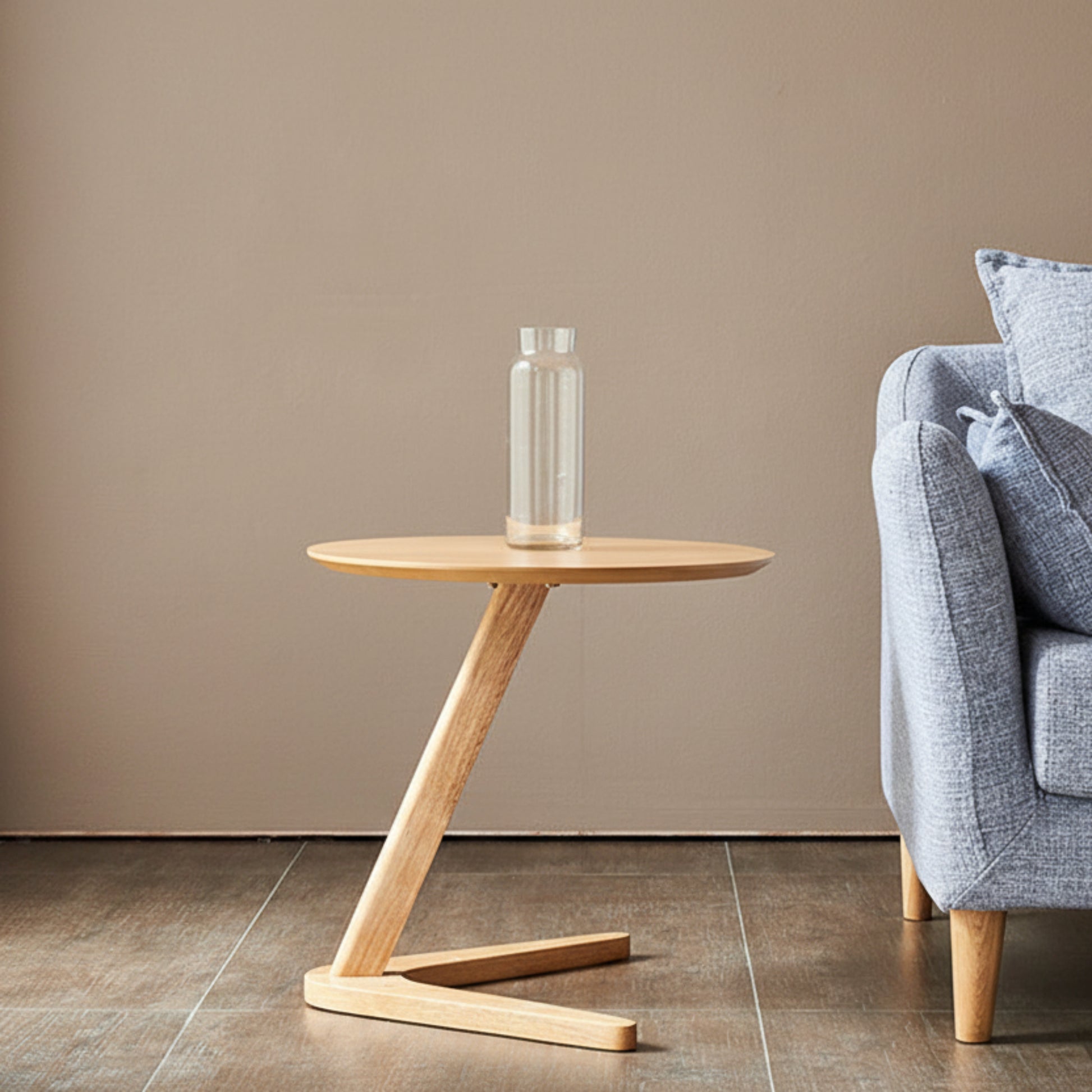 Wooden side table with a clear vase against a beige wall, next to a blue-gray sofa. Minimalist and natural side table. 
