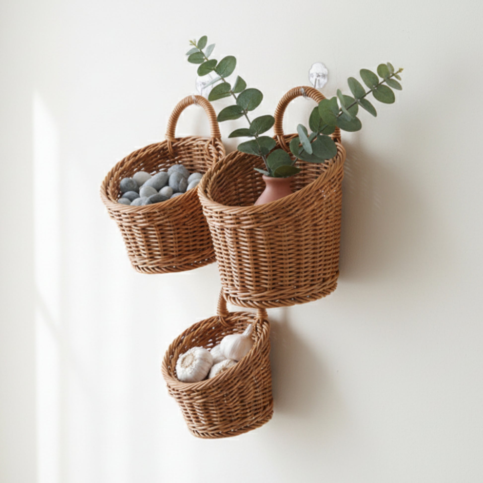 Three wicker baskets hanging on a wooden door, each containing different items. On a white wall. Kitchen, living room or any room. 