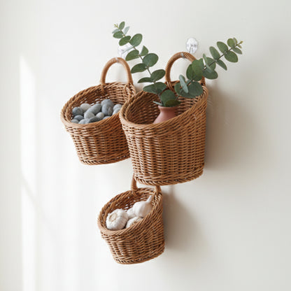 Three wicker baskets hanging on a wooden door, each containing different items. On a white wall. Kitchen, living room or any room. 