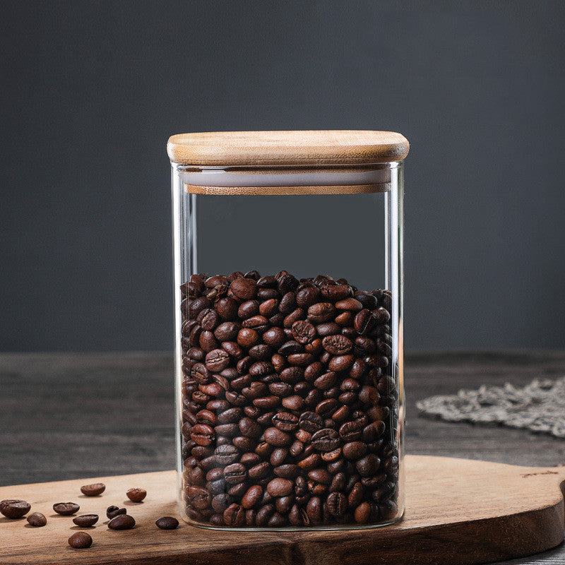 Jar with wooden lid filled with coffee beans on a wooden kitchen surface on a dark grey background. A warm minimalist interior with simple decor and simple design. Storage kitchen jar. 