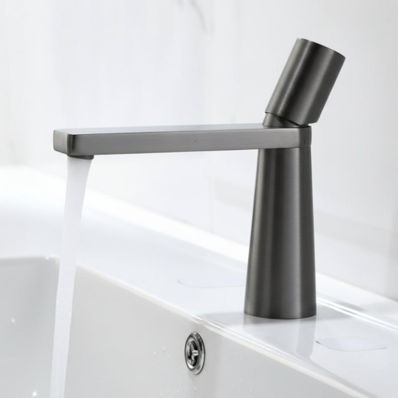 A grey colored basin faucet with a sleek design, displayed against a white background and running water.  Minimalist bathroom or kitchen faucet with premium copper faucet. Timeless design for warm and modern interiors.