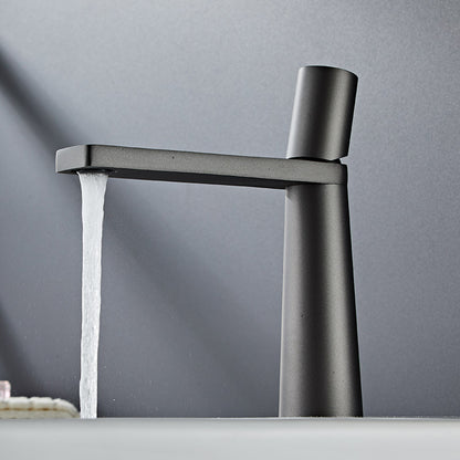 A grey colored basin faucet with a sleek design, displayed against a grey background and running water.  Minimalist bathroom or kitchen faucet with premium copper faucet. Timeless design for warm and modern interiors.