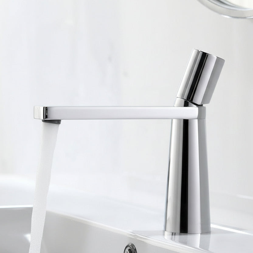 A silver colored basin faucet (small) with a sleek design, displayed against a dark background.  Minimalist bathroom or kitchen faucet with premium copper faucet. Timeless design for warm and modern interiors.