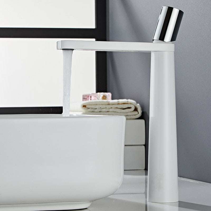 A white and silver colored basin faucet with a sleek design, displayed against a grey background and running water.  Minimalist bathroom or kitchen faucet with premium copper faucet. Timeless design for warm and modern interiors.