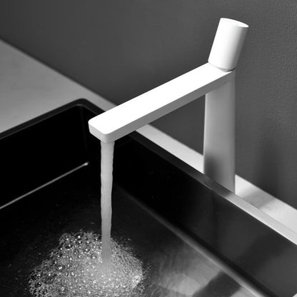 A white colored basin faucet with a sleek design, displayed against a grey background and running water.  Minimalist bathroom or kitchen faucet with premium copper faucet. Timeless design for warm and modern interiors.