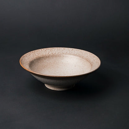 Ceramic bowl with speckled texture on a dark background. beige ceramic bowl on a dark surface. Natural textures and earthy, warm tones. Timeless minimalist and warm design.  
