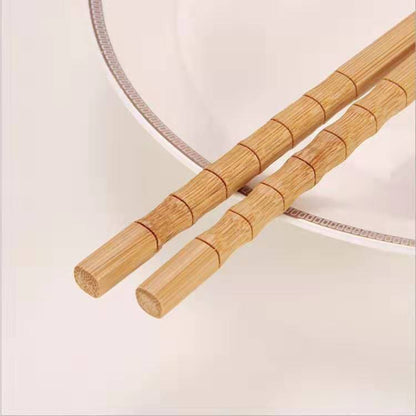 One pair of chopsticks on a plate and bright kitchen surface. Natural, unpainted, eco-friendly bamboo. 