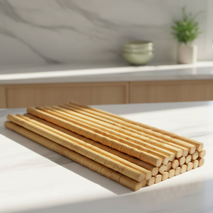 Stack of wooden chopsticks on a grey marble kitchen surface and grey marble background. Natural kitchen ambience and wooden/marble kitchen. Plant in the blurry background. Natural, unpainted, eco-friendly bamboo. 
