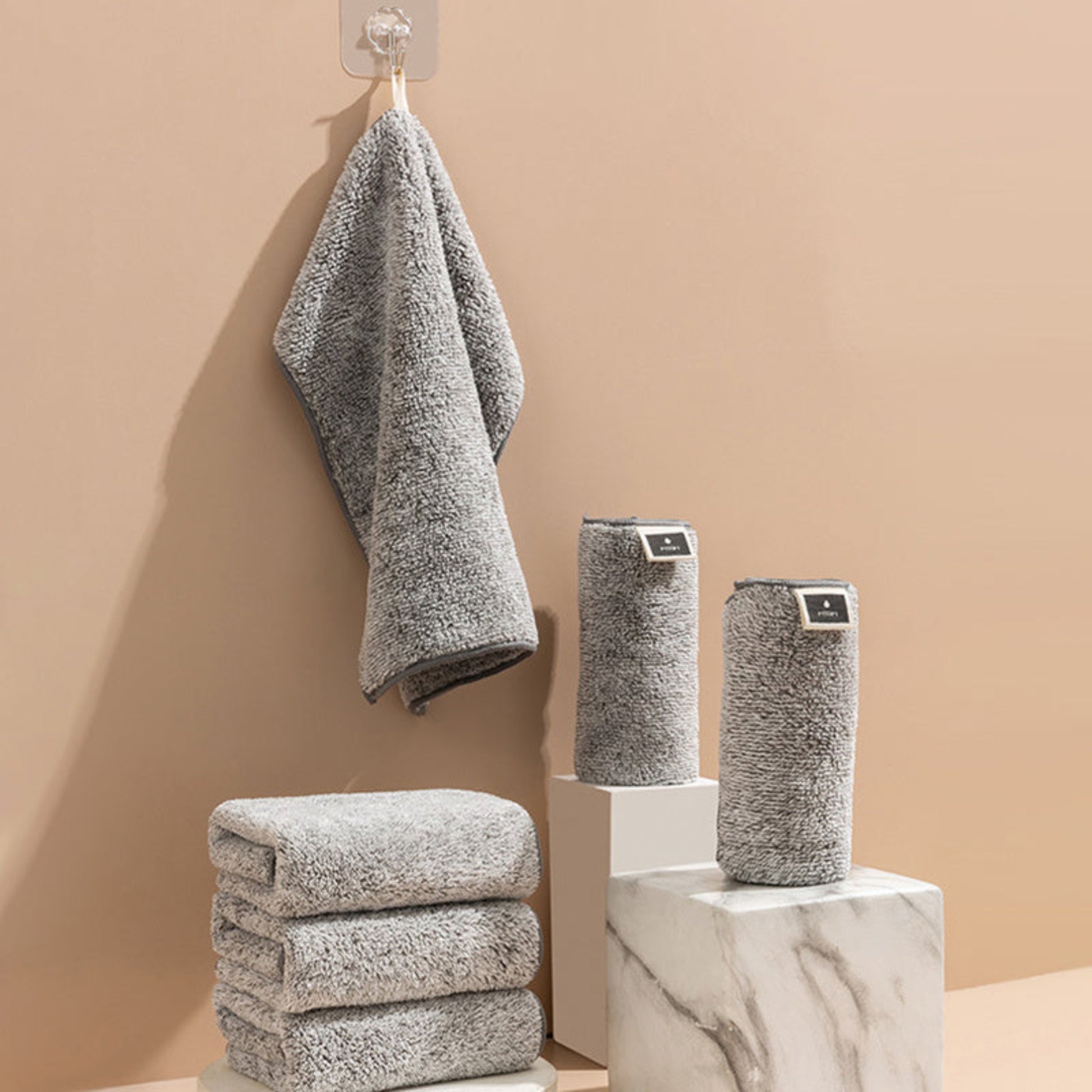 Gray textured towels on a beige wall with a marble surface. Scandinavian home decor. Grey super fine fiber towel Japanese style on a beige wall. 
