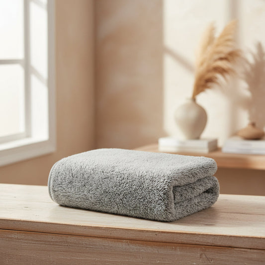 Folded gray towel on a wooden surface with a blurred indoor background. Wood and beige colors and texture. Dried flowers in the background. Scandinavian decor style. 