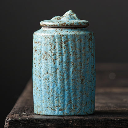 Blue and hand trimmed ceramic jar with lid on a dark wooden surface, with a dark background. Stylish kitchen decor. Modern and traditional. Timeless piece.