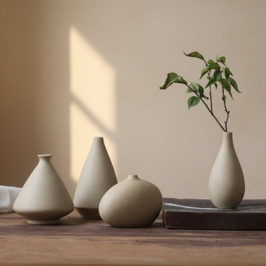 Set of four ceramic vases on a wooden surface with a minimal beige background. Warm minimalist ceramic decor interior with natural decor and simple design. Warmth, texture, and balance. Unburnt Ceramic. 