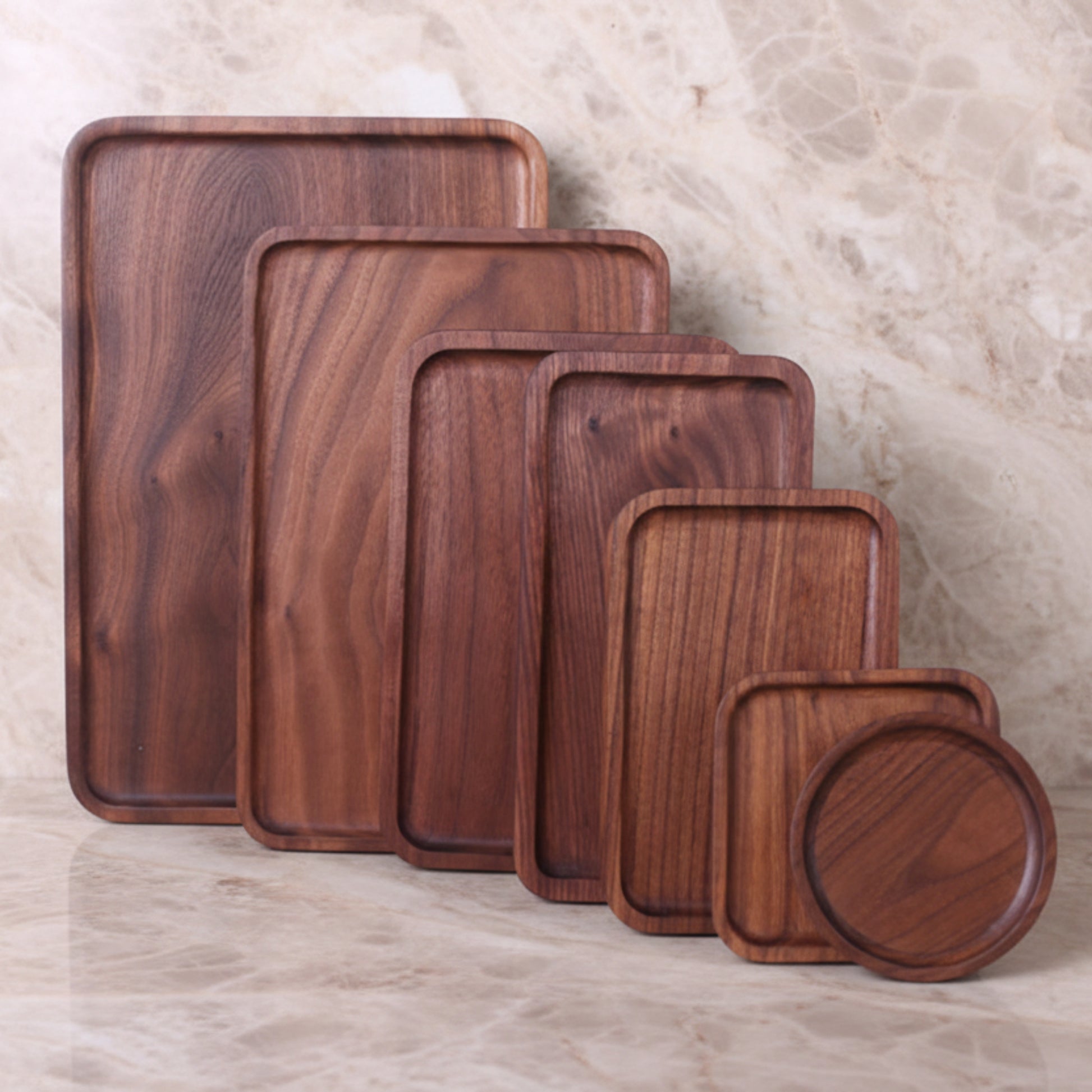 Set of wooden trays of different sizes on a textured marble kitchen surface and background. Earthy tones and whole wood. Calm, natural, peaceful and minimalist ambience. 