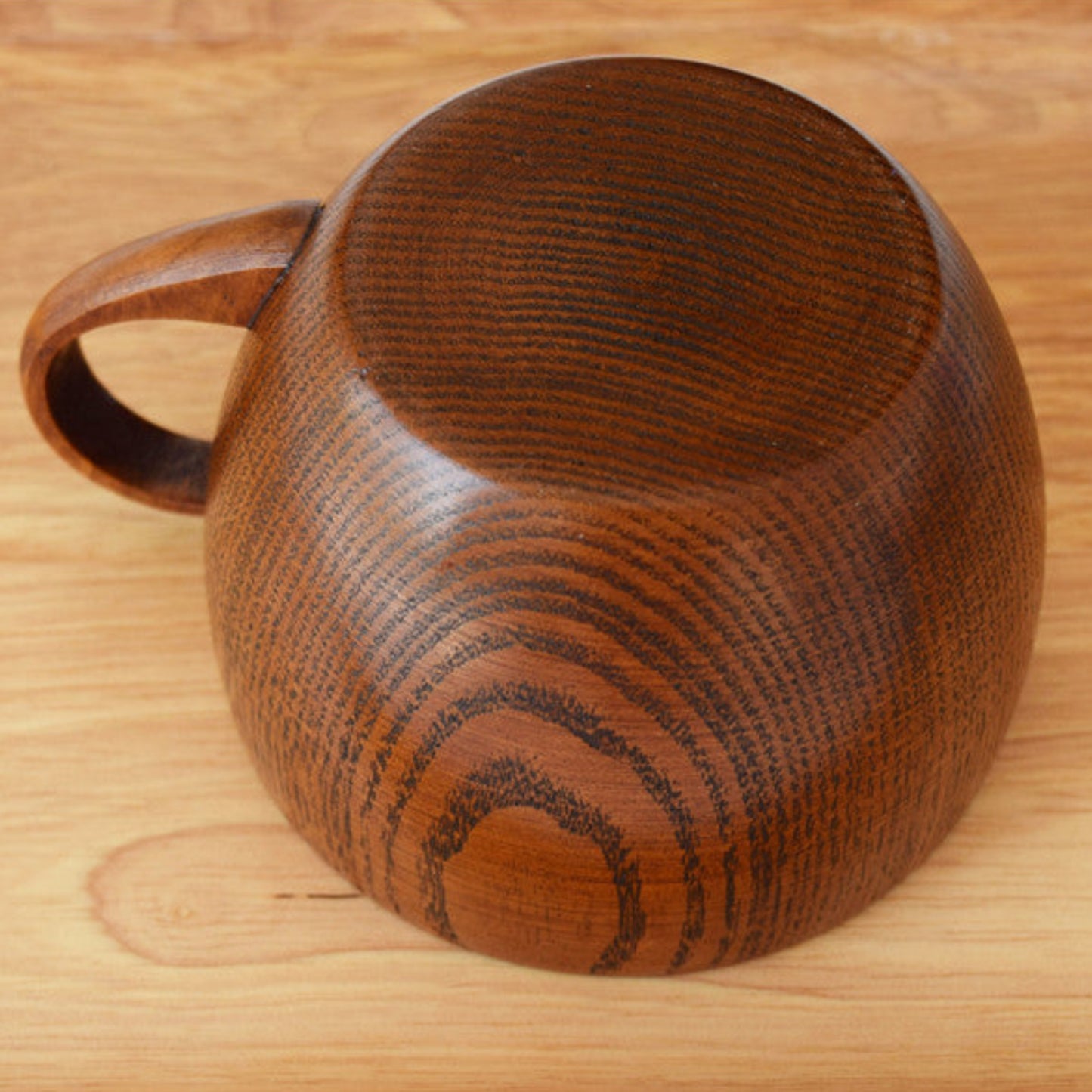 Whole wood mug on a wooden surface. Bottom pictured. Nature inspired and warm natural decor styling. 