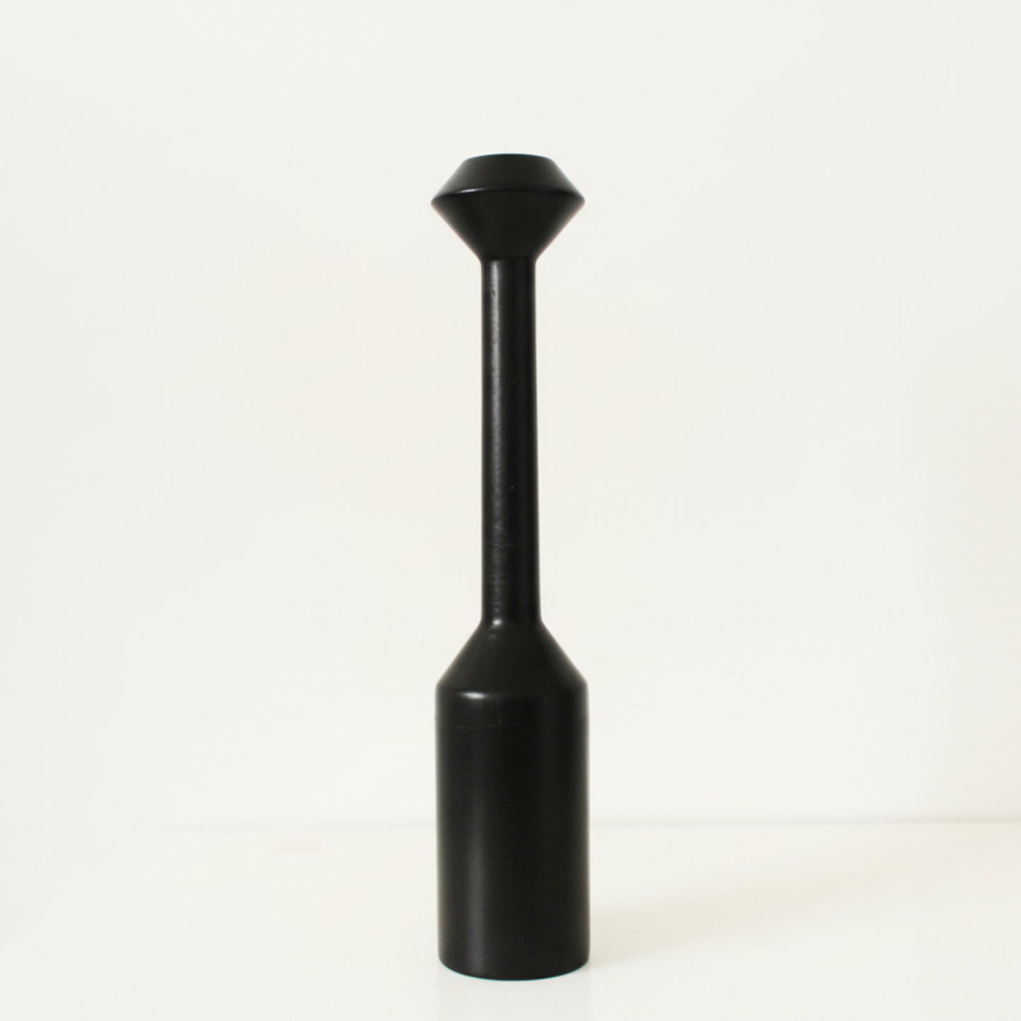 Black cylindrical large wooden candle holder with a conical top on a white background. Earthy and natural home decor. 